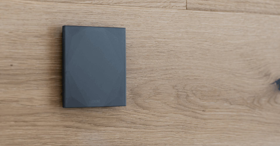 Černé skleněné tlačítko Loxone na dřevěném podkladu