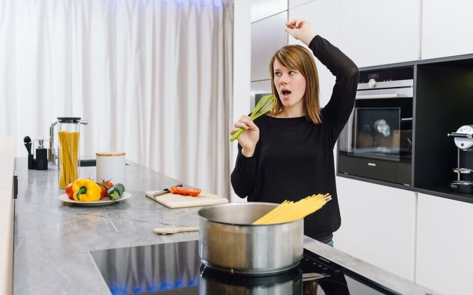 žena poslouchá hudbu v kuchyni