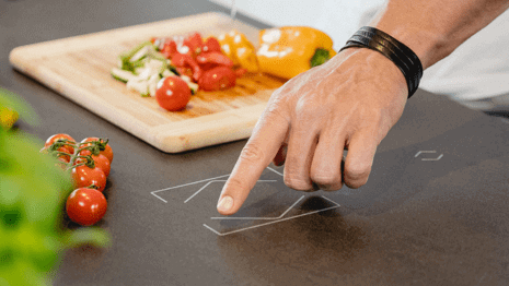 mužská ruka ovládá chytré tlačítko integrované v kuchyňské lince