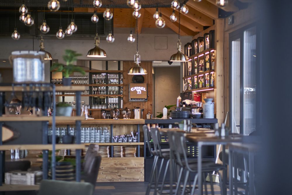 This is a view of the whole restaurant, including tables, hanging retro lights and the service counter.