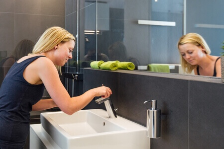 Woman getting ready at bathroom sink.