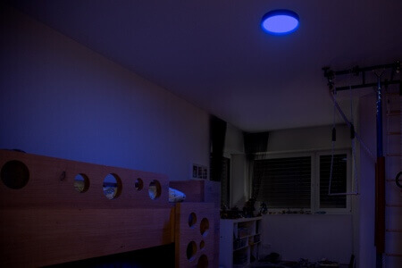 Ceiling light with dim blue light in bedroom at night.