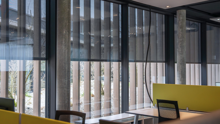 Wooden slats and intelligently controlled textile screens for optimum shading in an office