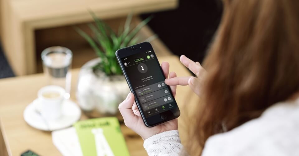 Kobieta trzyma w dłoni telefon z aplikacją Loxone