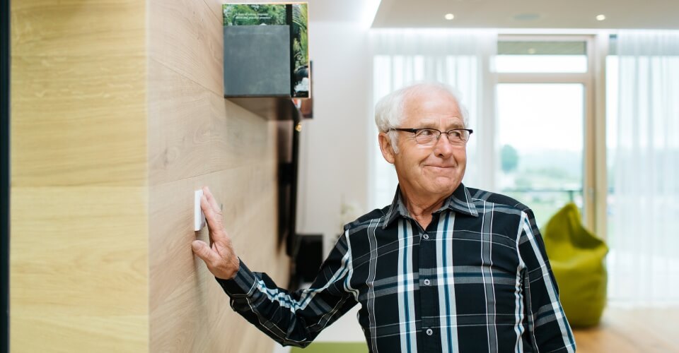 Starszy mężczyzna włącza przyciskiem światło