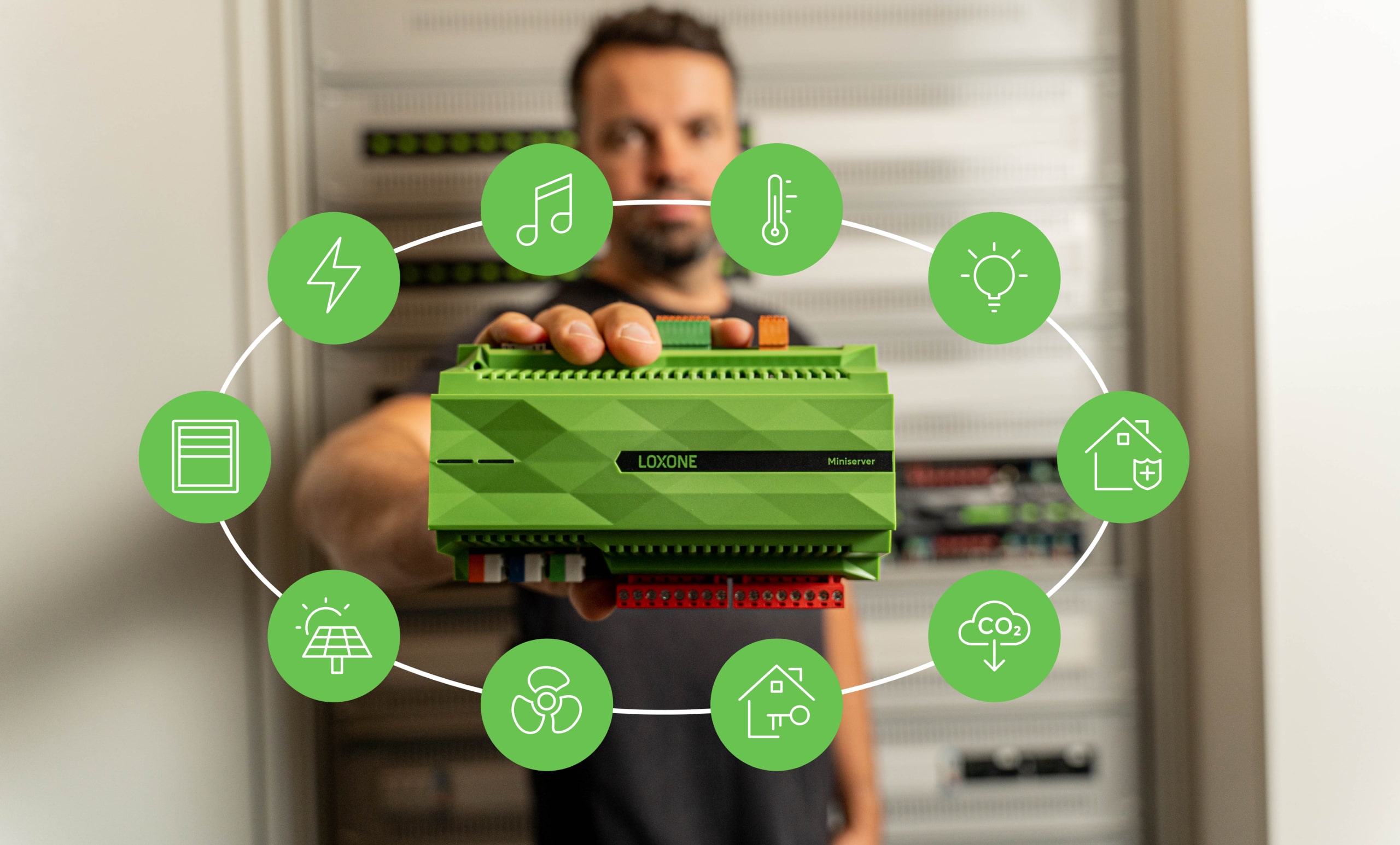 Mężczyzna trzymający w wyciągniętej dłoni Miniserver Loxone