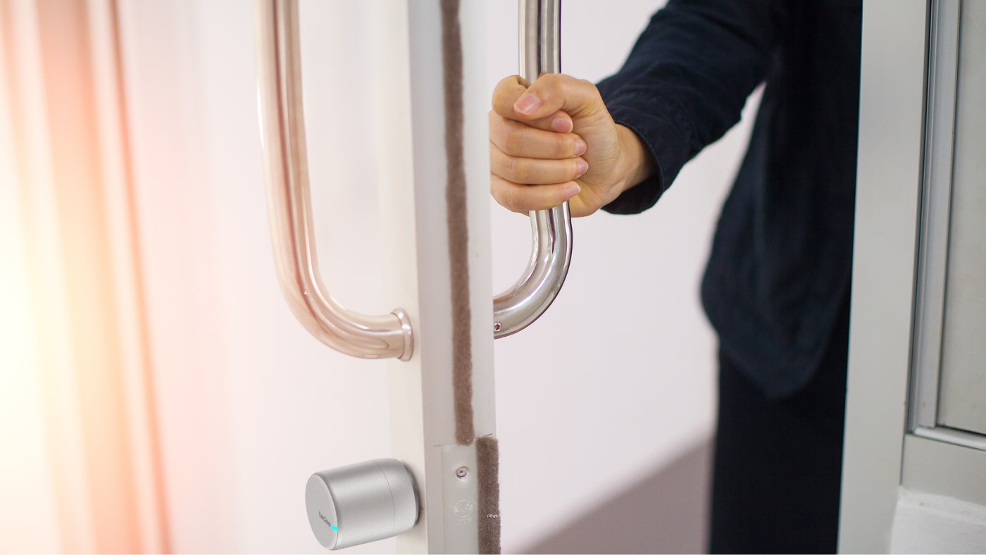 Dłoń otwierająca drzwi z zamkiem Tedee